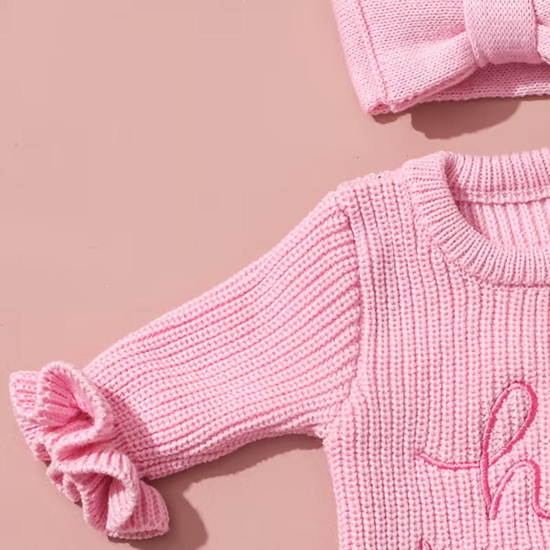 Welcome Baby Romper Set from House of Hide in soft pink ribbed knit featuring hi I'm new here embroidery, ruffled cuffs and hem for sweetness, snap button closure at bottom, coordinated bow headband accessory being presented as newborn photo prop set