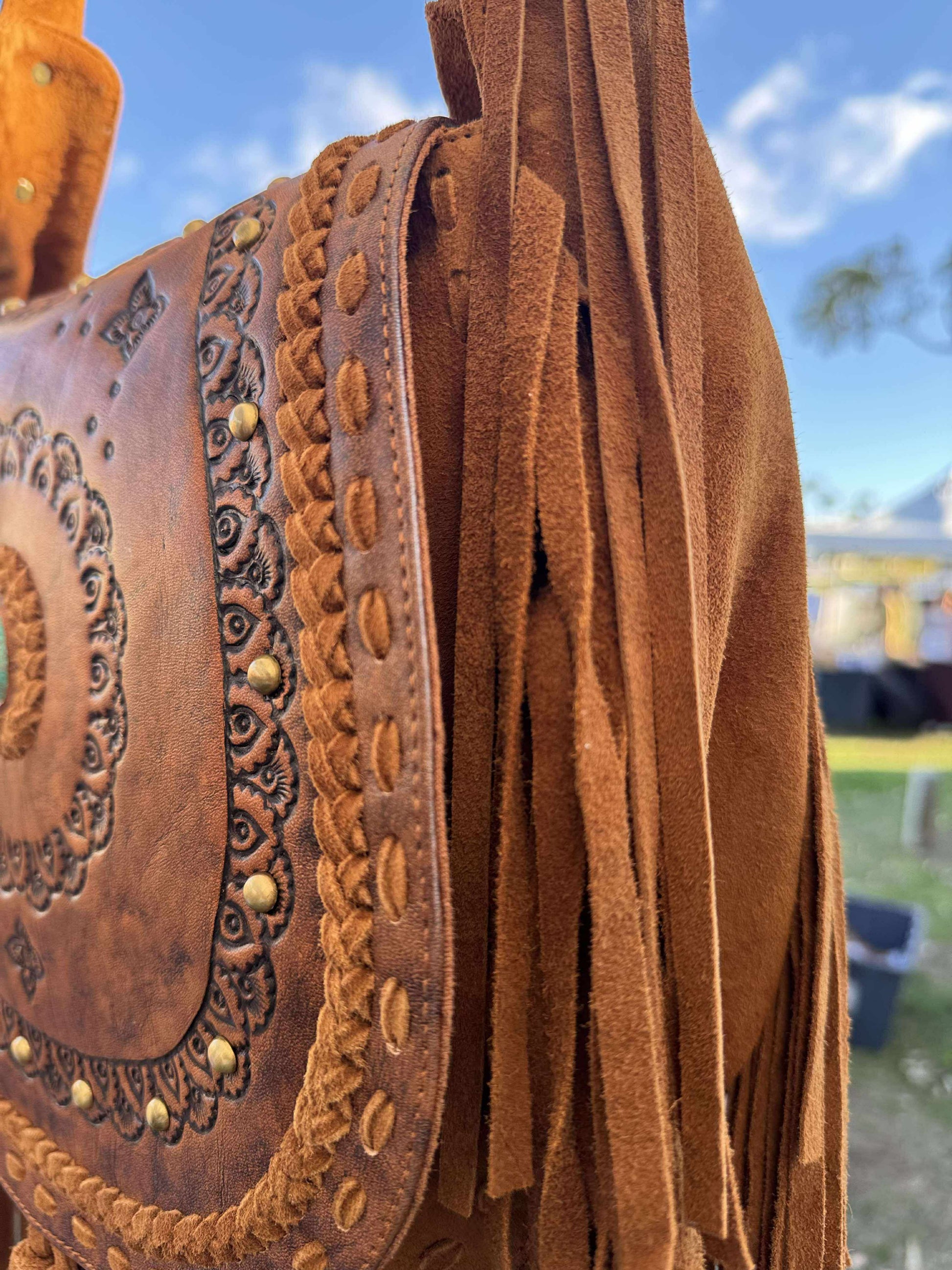 Western-style brown leather handbag for women, with long suede fringe, unique tooling, and adjustable crossbody strap – perfect for boho outfits and festivals.