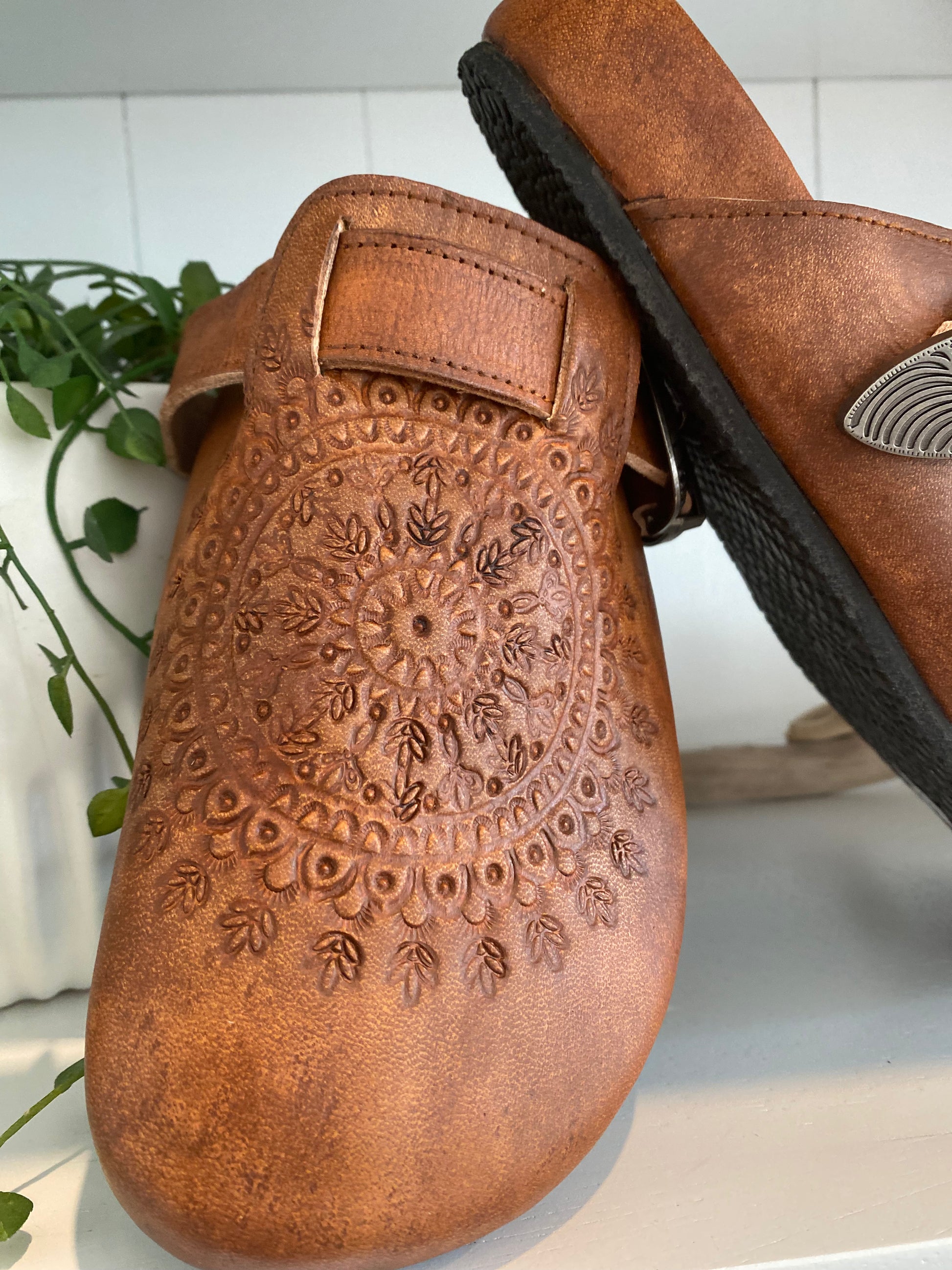 Western Buckle Boho Clogs with fringe trim – Focus on the fringe trim details alongside the brown leather and buckle, blending boho and western styles.