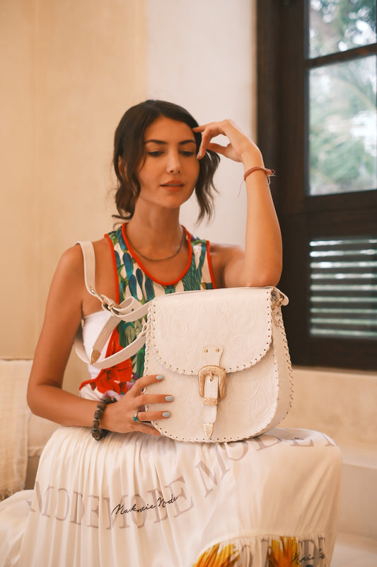 White leather crossbody bag with all-over hand tooling and rose gold hardware – boho handbag for weddings and summer styling.