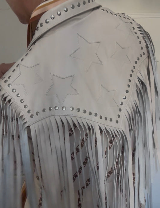 Woman wearing white leather fringe bolero with white star detail, styled with denim and boots in a western-inspired outfit.