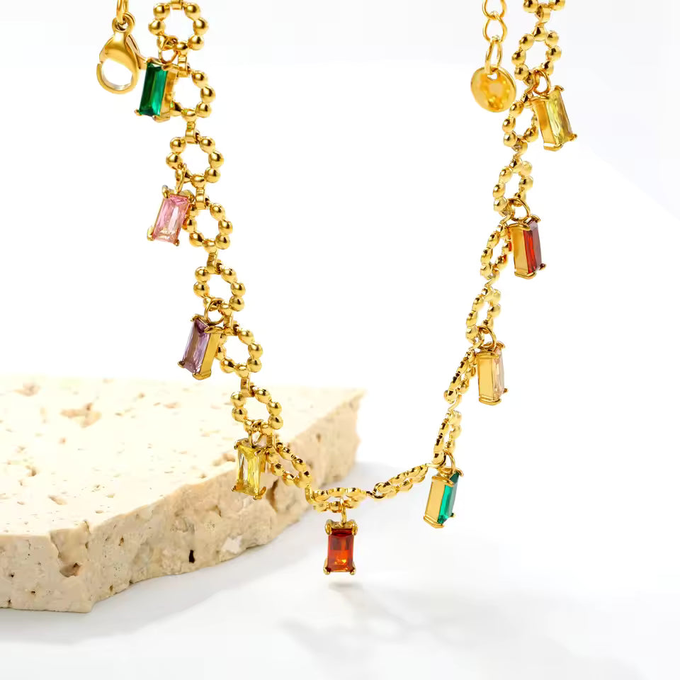 Gold necklace with colorful gemstones on a white background