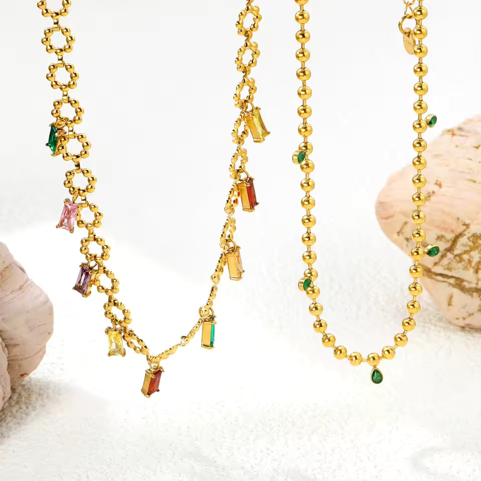 Gold necklaces with colorful pendants on a white background