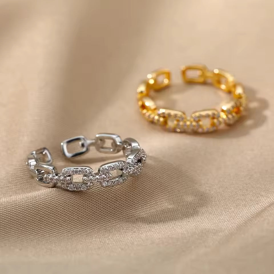 Gold and silver chain-link rings on a beige fabric background