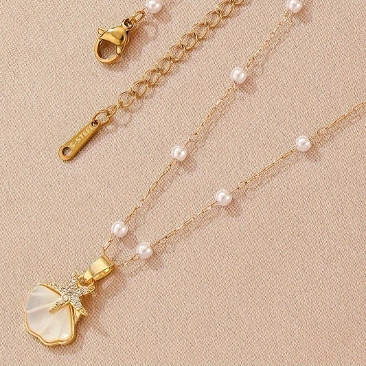 Golden pearl pendant necklace laying flat on a light surface