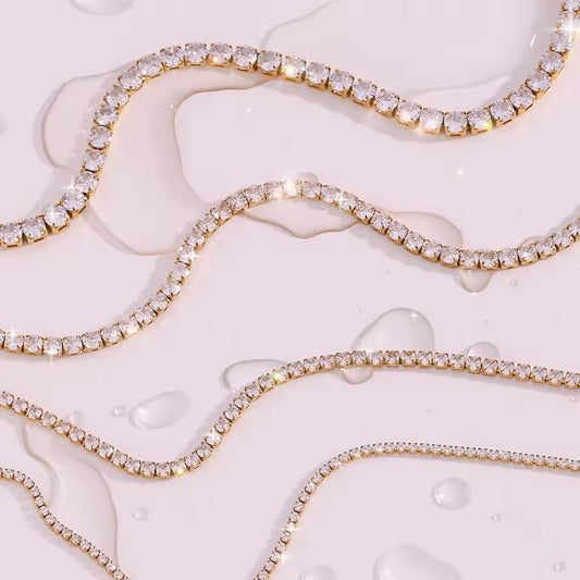 Gold necklace with clear gemstones on a textured white surface