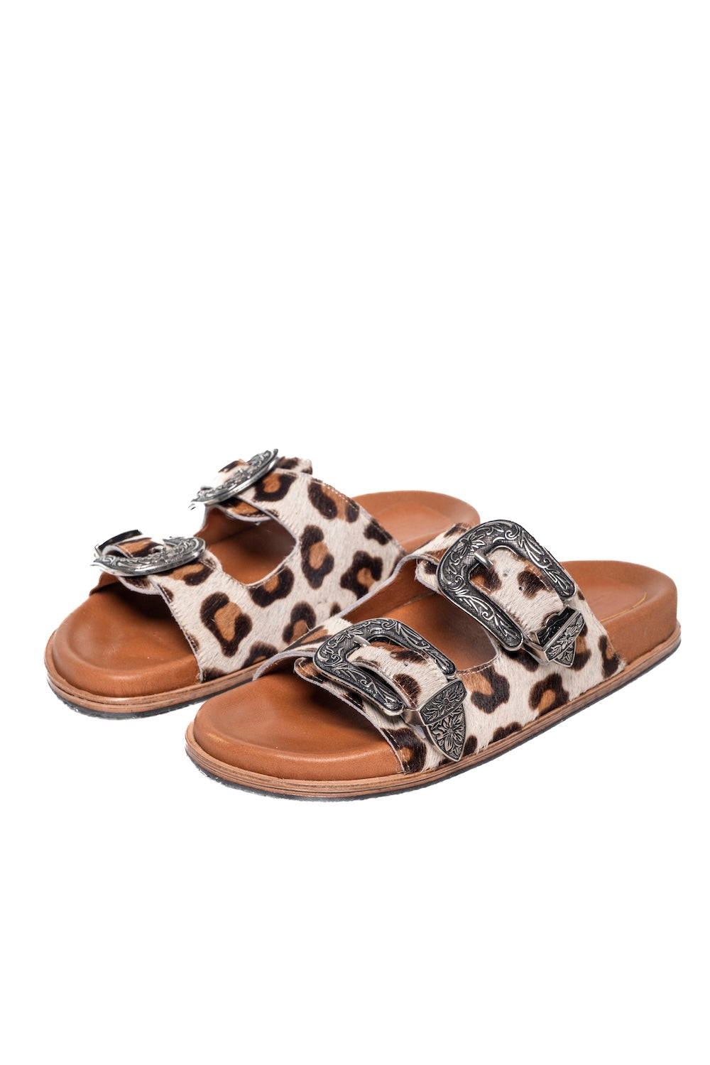 Close-up of leopard print leather slides featuring silver cowboy-style buckles and stud details,
