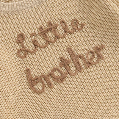 Baby boy wearing Little Brother knit jumper in beige
Close-up of embroidered Little Brother lettering on baby jumper