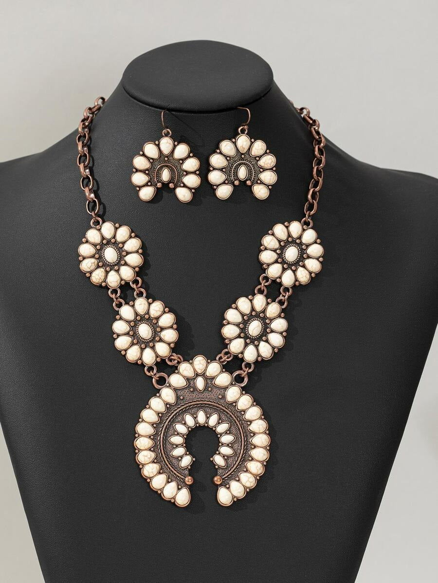 Rustic rodeo jewelry set closeup on a black mannequin, antique copper squash blossom necklace and earrings, white stone statement jewelry.