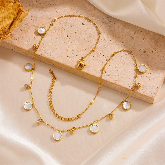 Gold necklace with circular pendants on a beige surface