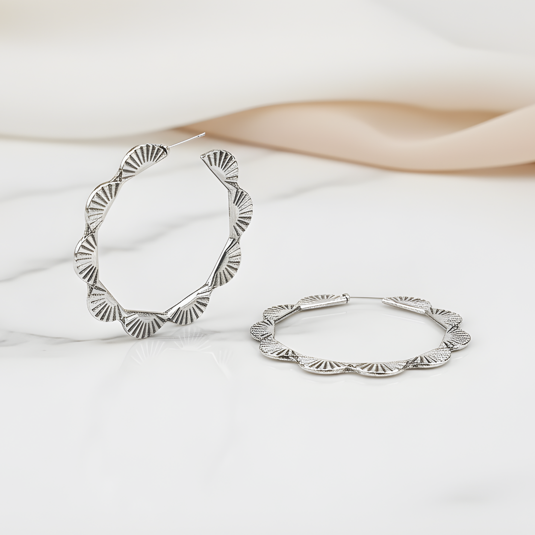 Sea Whisper Earrings featuring wavy edge silver hoops on white background