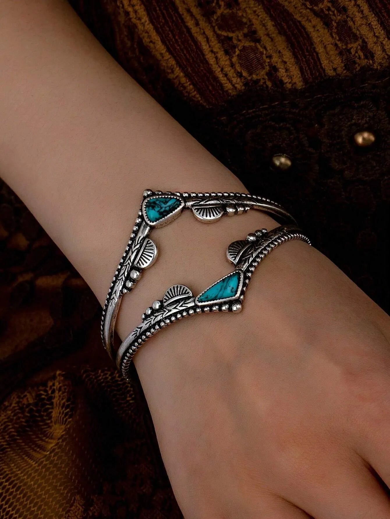 Turquoise cuff bangle bracelet on a wrist against a dark background