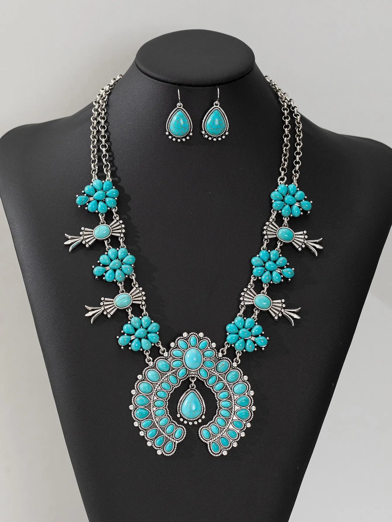 Turquoise pendant necklace on a black mannequin with a gray background